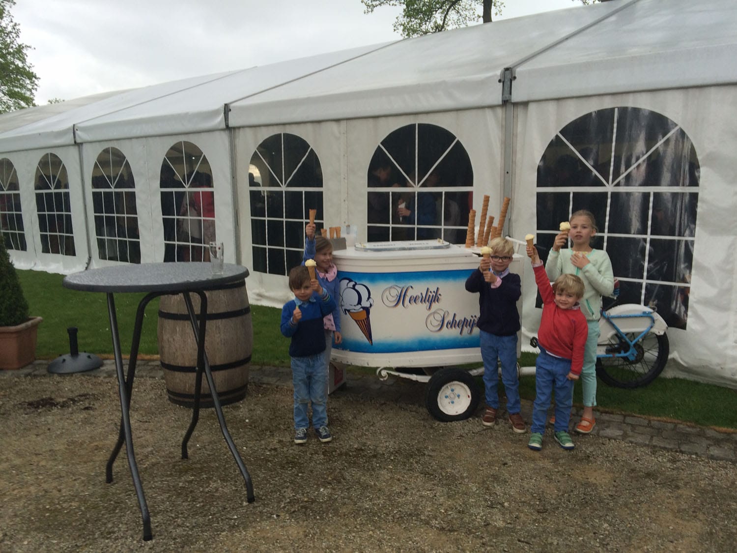 De ijskar bij een witte feesttent, kinderen met een ijshoorntje in de hand